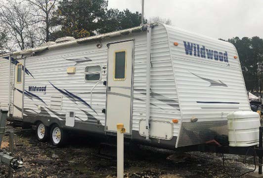 Photo of stolen white camper with "Wildwood" spelled across the front in blue lettering. 